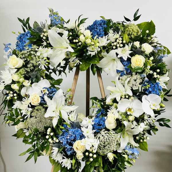 Large floral wreath with white and blue flowers on a wooden easel