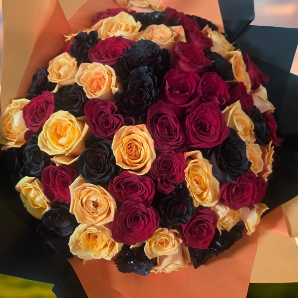 Bouquet of red, peach, and black roses wrapped in peach and black paper