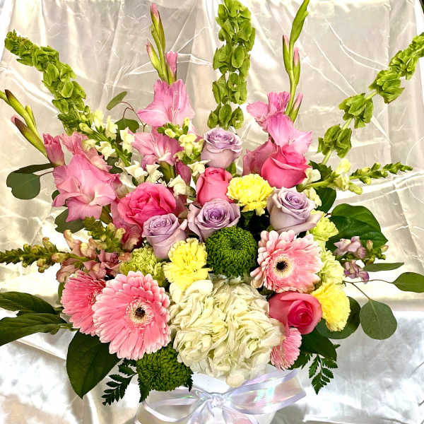 Pink and lavender bouquet with gerbera daisies and roses in a white vase