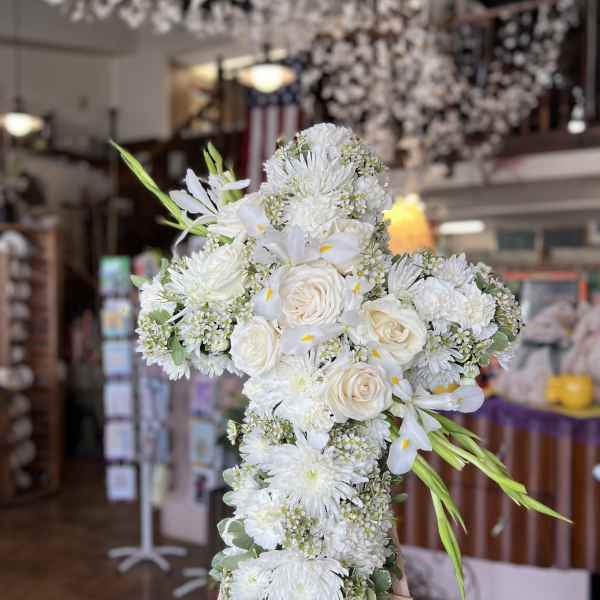 White floral cross arrangement on an easel