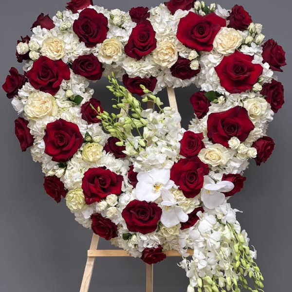 Heart-shaped floral arrangement of red and white roses on an easel