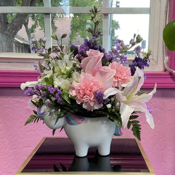 Pink and purple flower arrangement in a unicorn-shaped vase