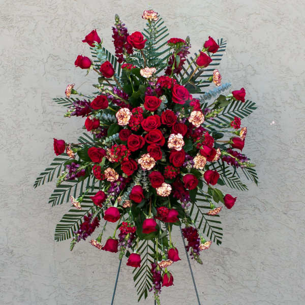 Large standing spray of red roses and mixed flowers on an easel