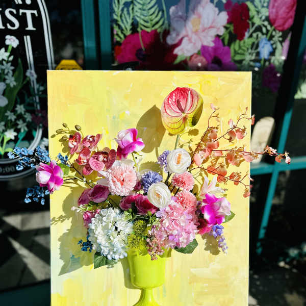 Colorful floral arrangement in a lime green vase on a yellow canvas