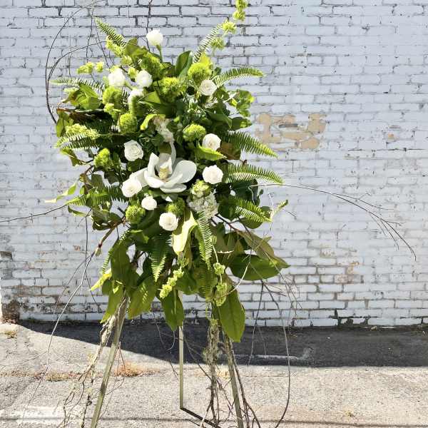 Tall white and green floral standing arrangement on a tripod easel