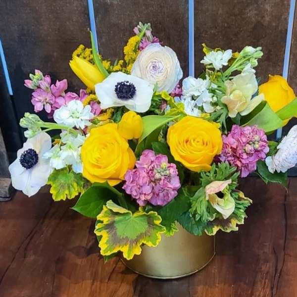 Mixed bouquet of yellow and white flowers in a gold container
