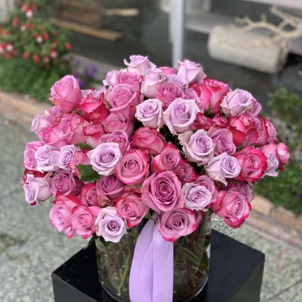 Bouquet of pink and lavender roses in a glass vase with a ribbon