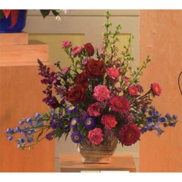 Mixed bouquet of red, pink, and blue flowers in a glass vase