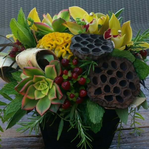 Mixed bouquet with succulents, yellow orchids, and lotus pods in a black vase