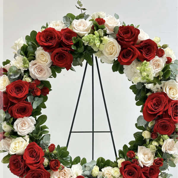 Circular wreath of red and white roses on a black stand