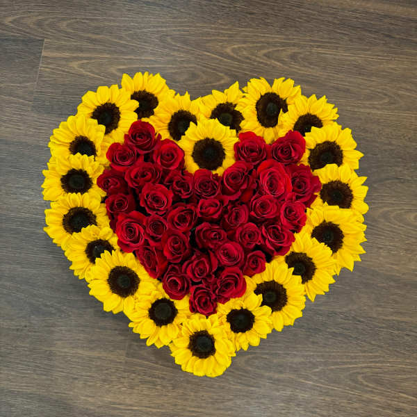 Heart-shaped arrangement of red roses bordered by yellow sunflowers