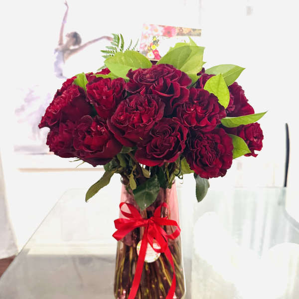Bouquet of deep red roses in a glass vase with a red ribbon