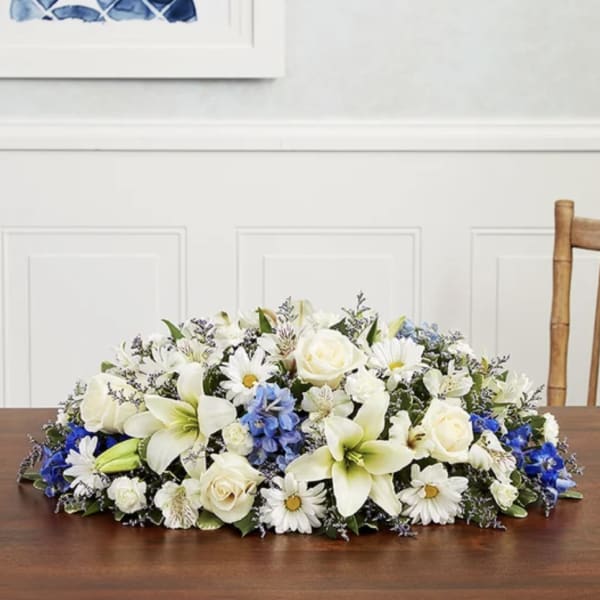 Low floral centerpiece with white lilies, roses, and daisies