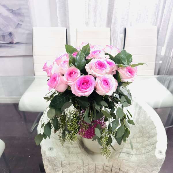 Pink roses arranged in a vase with trailing greenery