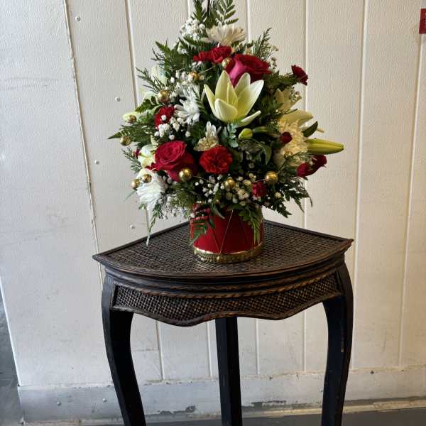 Christmas floral arrangement in a red container with a gold star topper