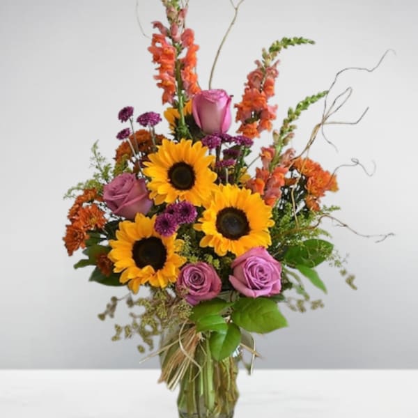 Sunflowers and purple roses in a glass vase