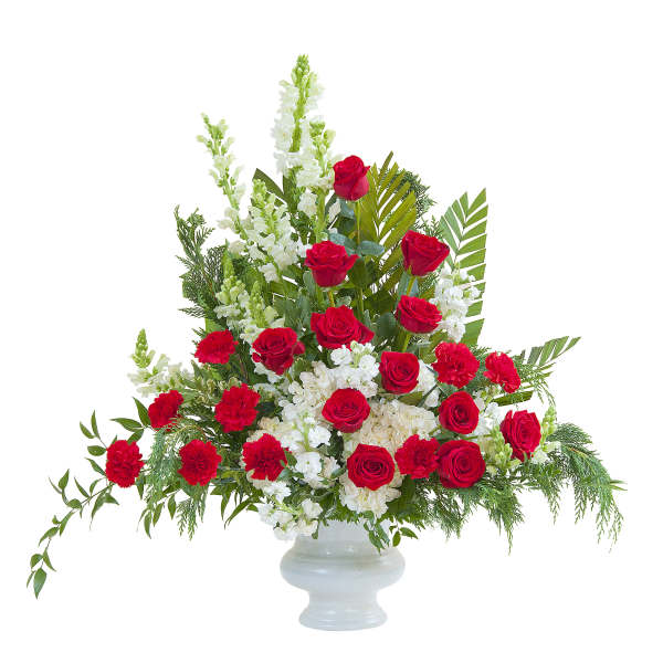 Tall red and white floral arrangement with roses and carnations in a white pedestal vase