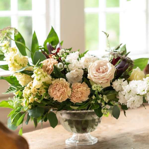 Mixed pastel floral arrangement in a clear glass compote vase