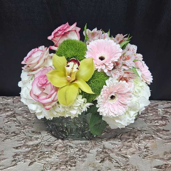 Pink roses and gerbera daisies with a yellow orchid in a low vase