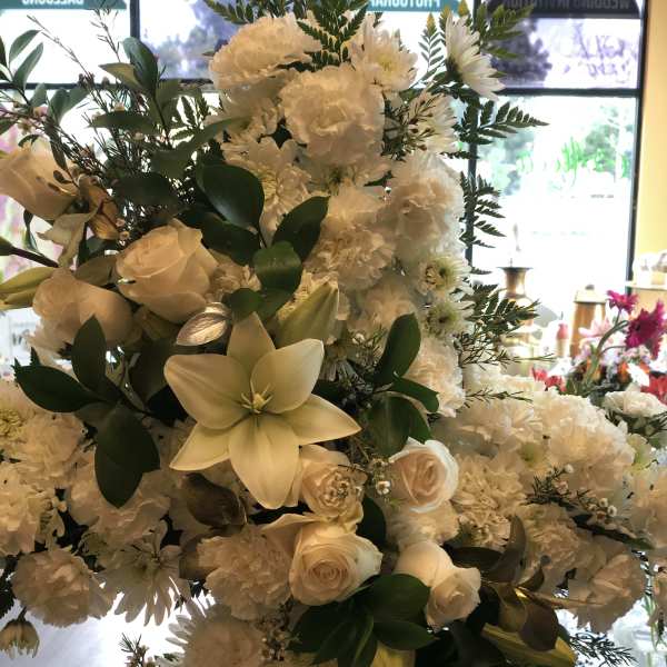 White floral arrangement with roses, lilies, and carnations
