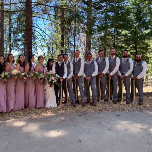 Wedding party in mauve dresses and gray suits holding bouquets outdoors