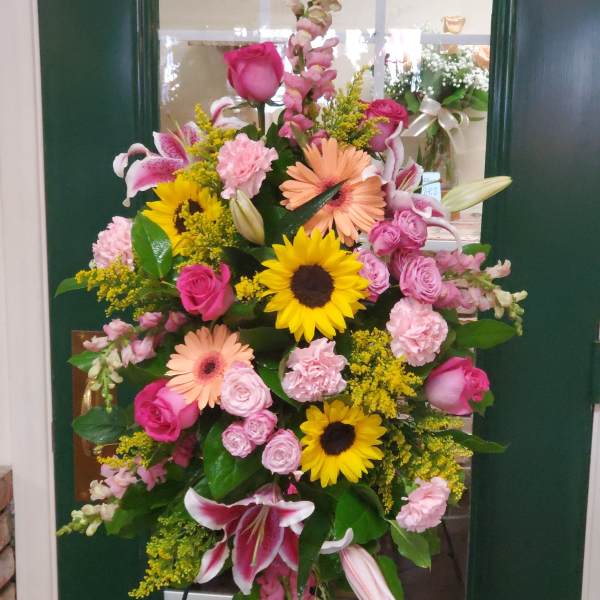 Large standing floral spray with pink, yellow, and peach blooms