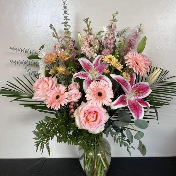 Pink lilies, roses, and gerbera daisies in a glass vase