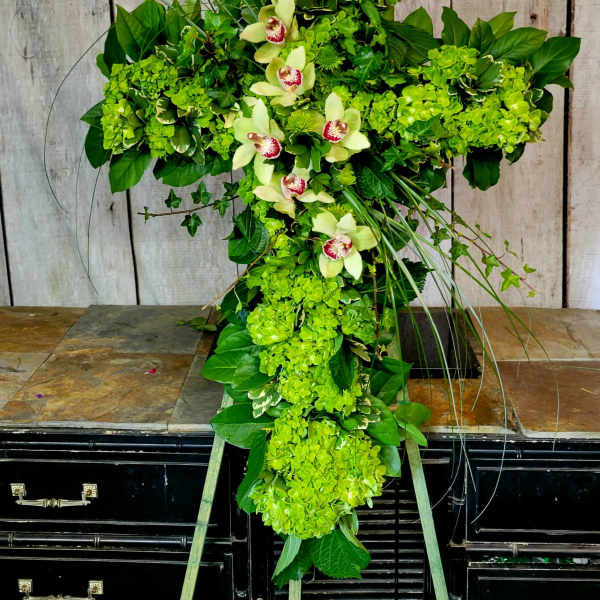 Green floral cross with orchids and hydrangeas on a stand