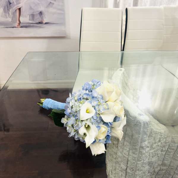 White calla lily and blue hydrangea bouquet on a glass table
