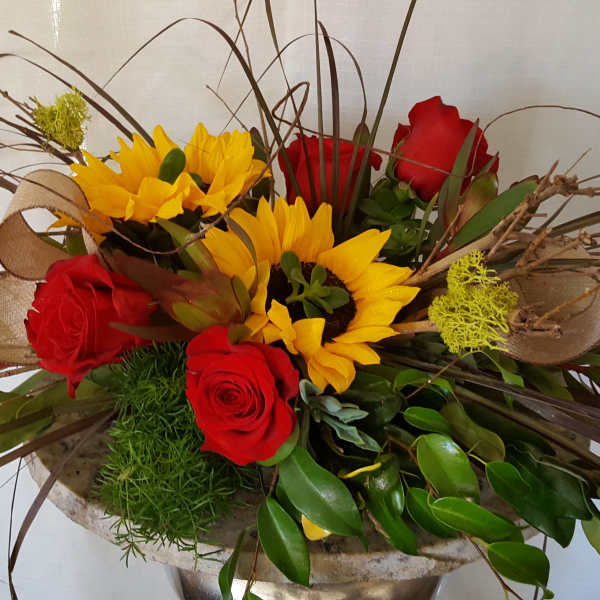 Arrangement of red roses and yellow sunflowers in a low container