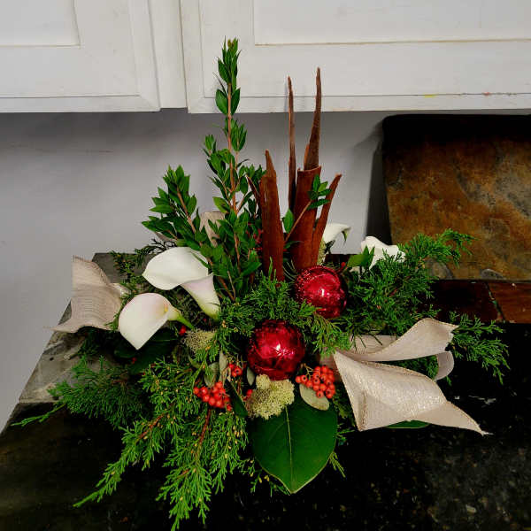 Holiday arrangement with white calla lilies, red ornaments, and ribbon