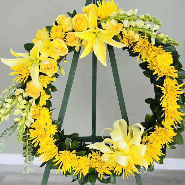 Yellow floral wreath on a stand with roses and lilies