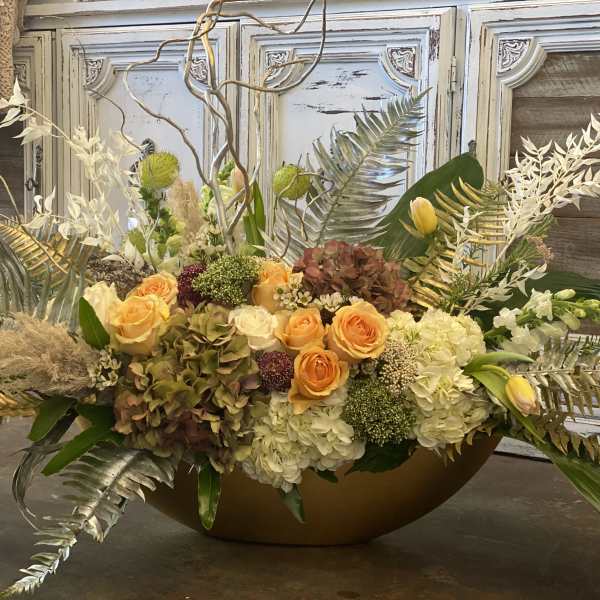 Large floral centerpiece with orange roses and white hydrangeas in a low bowl
