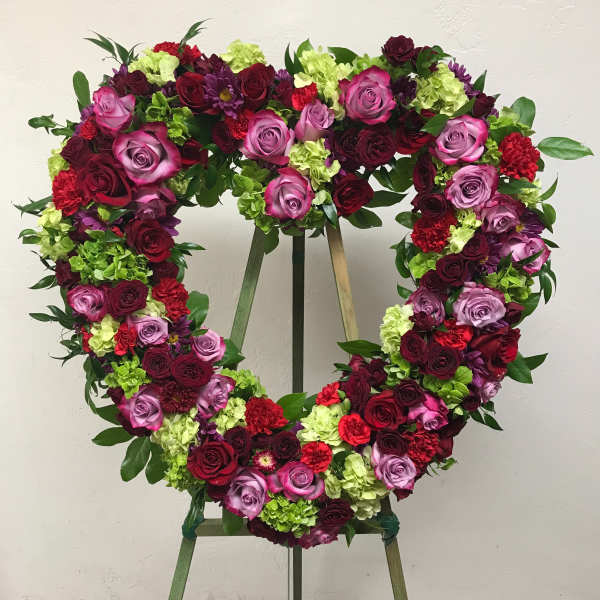Heart-shaped floral wreath on an easel with roses and carnations