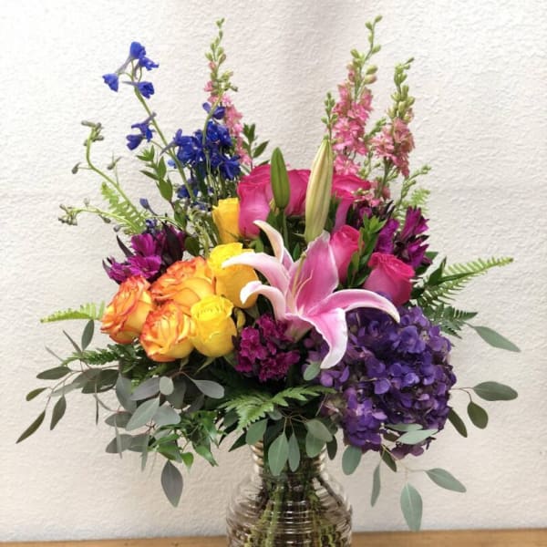 Colorful mixed bouquet in a clear glass vase with roses and lilies