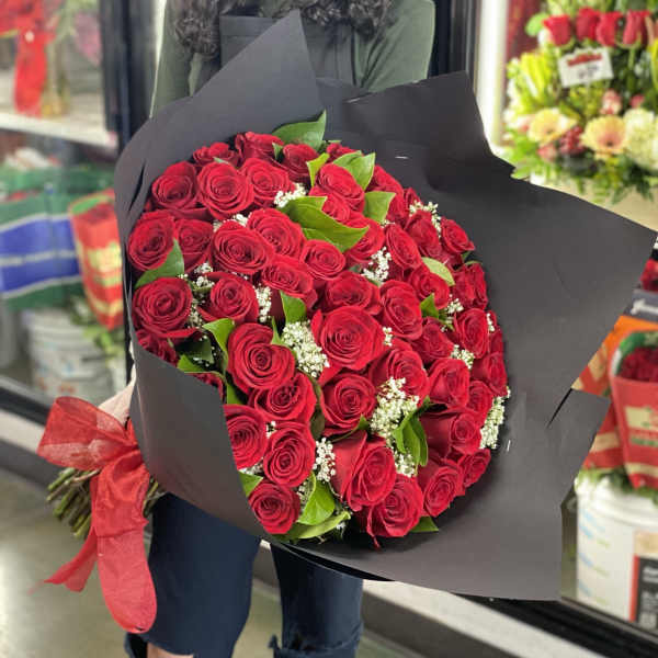 Large bouquet of red roses wrapped in black paper with a red ribbon