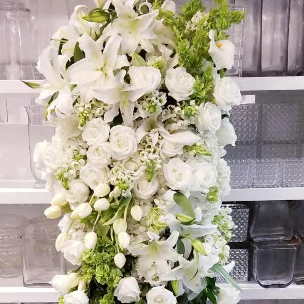Tall white floral standing spray with lilies and roses on an easel
