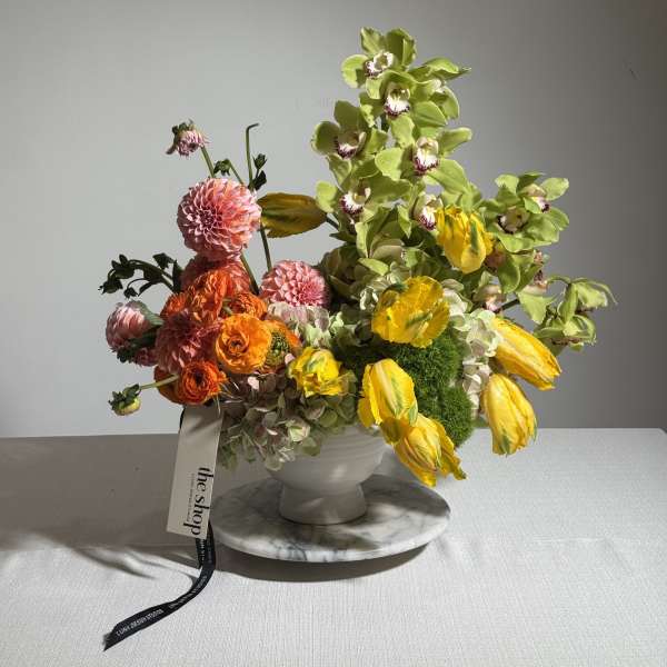 Colorful floral arrangement in a white vase with yellow and pink blooms