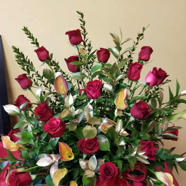 Red rose arrangement with calla lilies and greenery in a vase