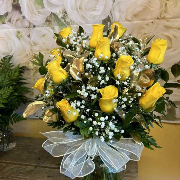 Yellow roses with baby's breath in a glass vase and white bow