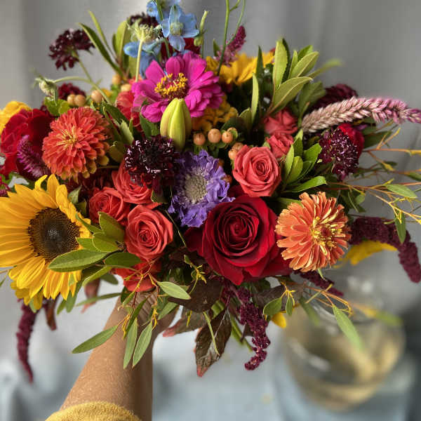 Handheld bouquet with sunflowers, roses, and mixed colorful blooms