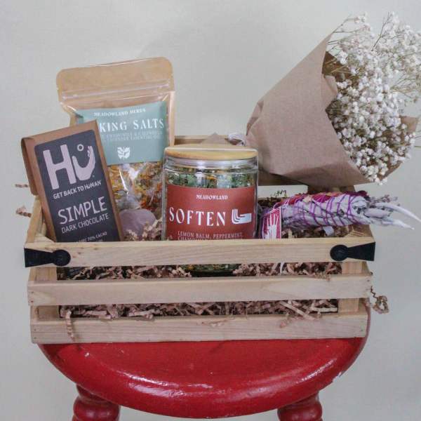 Gift basket with chocolates, bath salts, tea, and a small bouquet of white baby's breath