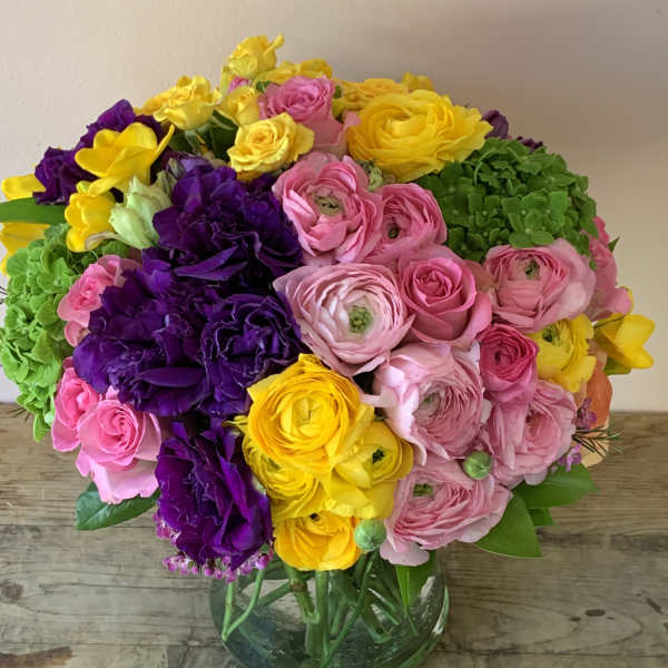 Bright bouquet of pink, yellow, and purple flowers in a glass vase