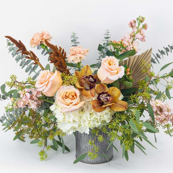 Peach roses and orchids in a ribbed metal vase