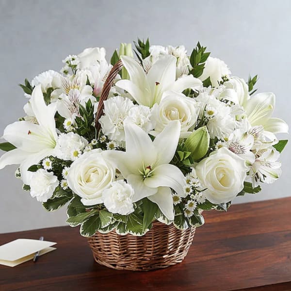 White lilies and roses arranged in a wicker basket