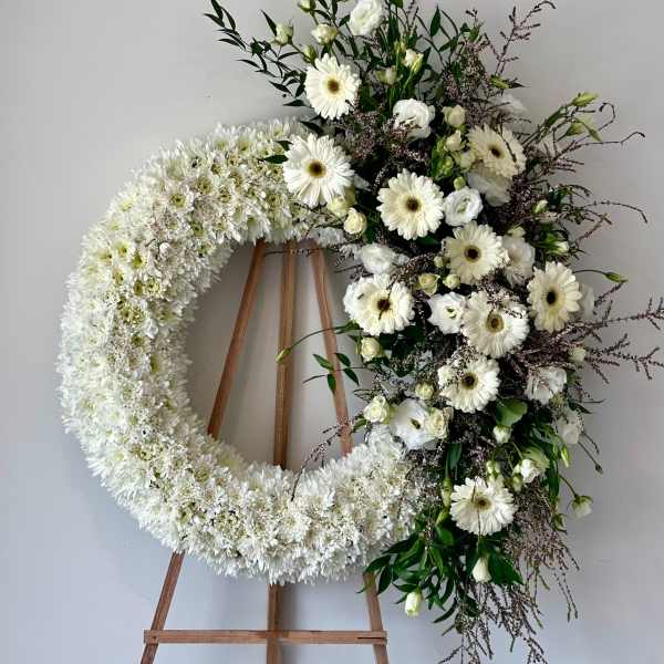 White floral wreath with a cascading spray on a wooden easel