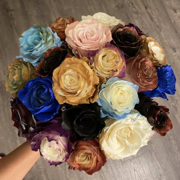 A hand holds a bouquet of multicolored roses.