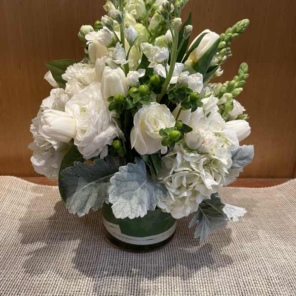 White floral arrangement in a round vase with silvery foliage