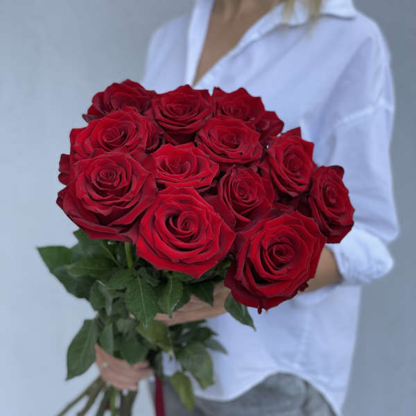 Bouquet of red roses held by a person in a white shirt