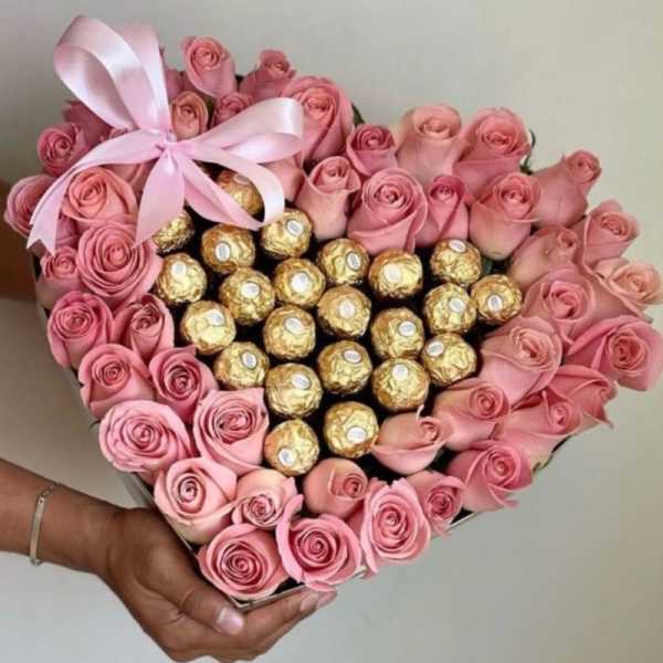 Heart-shaped box of pink roses with gold-wrapped chocolates and a pink ribbon